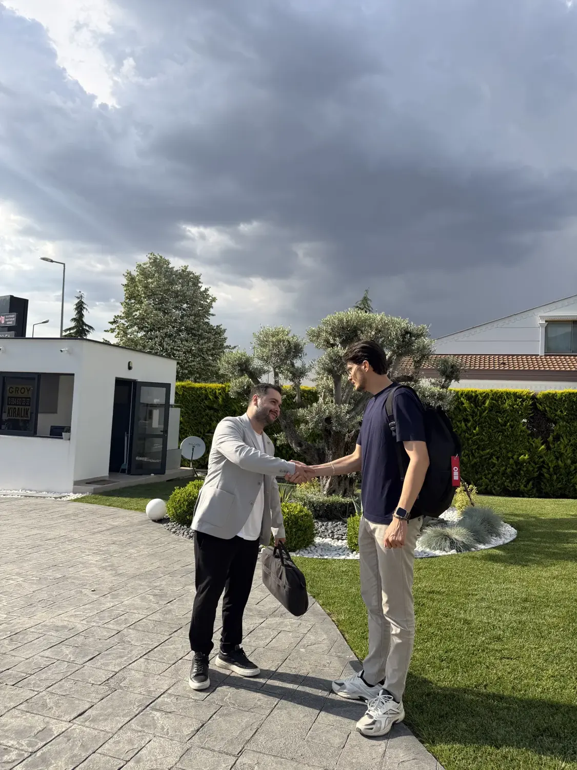 Bir tesisin önünde el sıkışan iki kişi